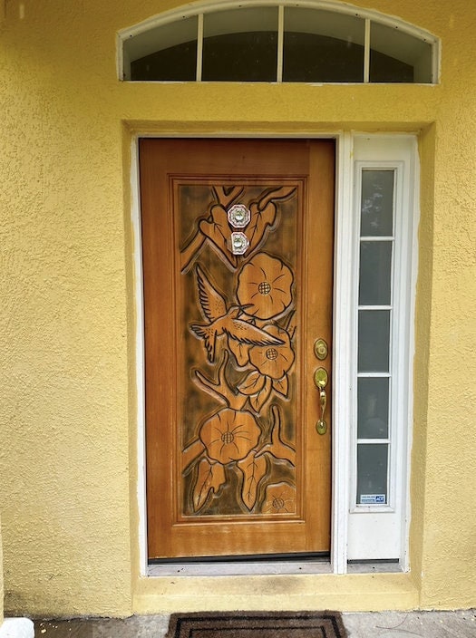 Image depicts a brown Brazilian Mahogany wood Entryway Door with hand carved flying birds and flowers.